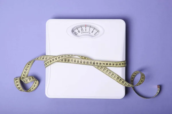 floor scales and tape measure on a colored background top view. Healthy lifestyle concept, healthy eating. Body weight control.