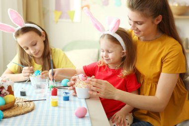 Anne ve kızları bayram için Paskalya yumurtası boyuyorlar. Paskalya, gelenekler.