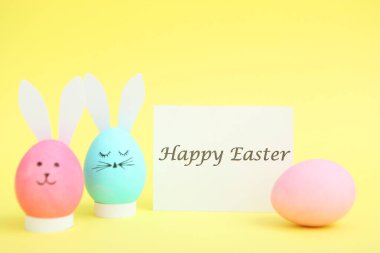 Renkli arka planda sevimli yüzleri ve kulakları olan Paskalya yumurtaları.