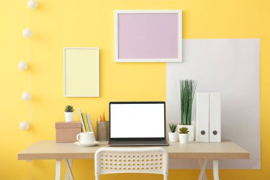 Modern bir dizüstü bilgisayarla duvarın yanındaki işyerinde. Bir öğrencinin, tasarımcının, yaratıcı kişinin modern işyeri..