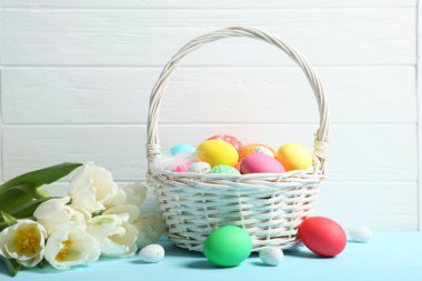 Sepette Paskalya yumurtası ve masada çiçekler. Metin eklemek için yeri olan neşeli paskalya arkaplanı.