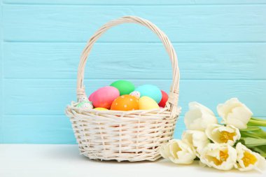 Sepette Paskalya yumurtası ve masada çiçekler. Metin eklemek için yeri olan neşeli paskalya arkaplanı.
