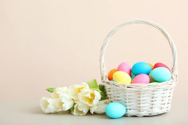 Sepette Paskalya yumurtası ve masada çiçekler. Metin eklemek için yeri olan neşeli paskalya arkaplanı.
