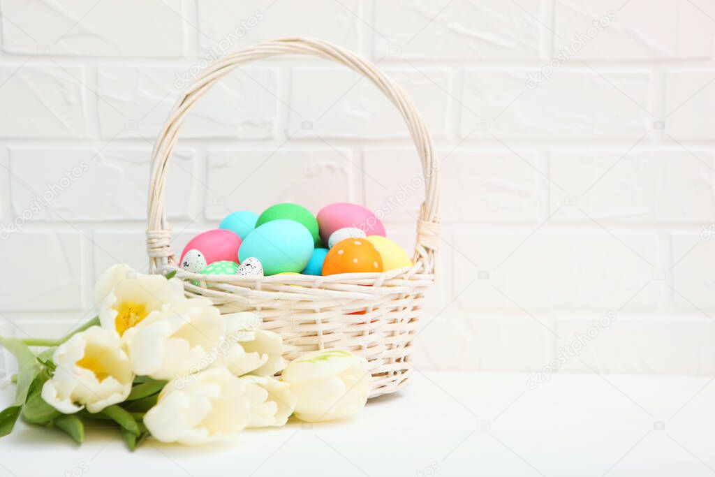 Easter eggs in a basket and flowers on the table. Festive easter background with place to insert text.