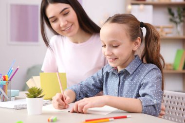Annem kızın ödevlerini yapmasına yardım eder. Çocuklar ve ebeveynler.