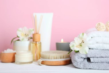 Masanın üzerinde havlular ve çiçekler olan spa kompozisyonu ve yazı için yer. Vücut bakımı, rahatlama