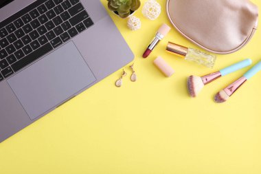 Renkli arka plan görünümlü makyaj malzemeleri ve modern laptop. Güzellik Günlüğü Konsepti