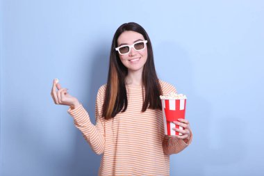 Renkli arka planda patlamış mısırı olan kız. Bir film izle, 3 boyutlu film..