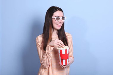 Renkli arka planda patlamış mısırı olan kız. Bir film izle, 3 boyutlu film..