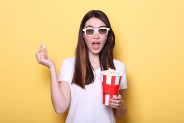 Renkli arka planda patlamış mısırı olan kız. Bir film izle, 3 boyutlu film..