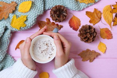 Sonbahar kompozisyon üst görünümü. Ellerde ve sonbahar yapraklarında bir fincan kahve