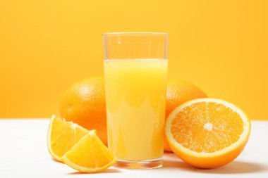 Bardakta portakal suyu, masada portakal ve portakal dilimleri..