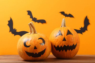 Cadılar Bayramı için renkli arkaplanda boyalı yüzleri olan balkabakları.