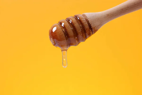 蜂蜜を木のスプーンから垂らし明るい色の背景に蜂蜜を — ストック写真