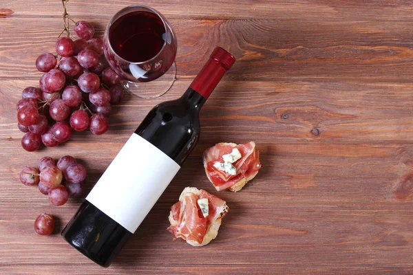 red wine and snacks on the table top view. Wine, prosciutto, cheese, baguette, grapes, honey.