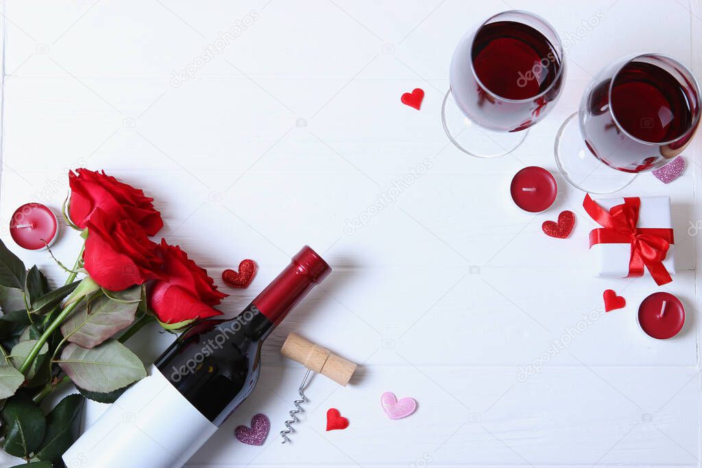 Red wine, hearts, red roses and gifts on a colored background top view.