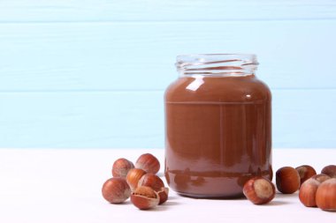 Renkli bir arka planda cam kavanozda çikolata ezmesi. Çikolata yağı, çikolata sosu..