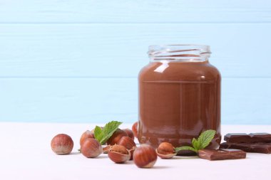 Renkli bir arka planda cam kavanozda çikolata ezmesi. Çikolata yağı, çikolata sosu..