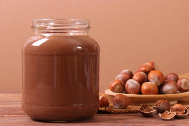 Renkli bir arka planda cam kavanozda çikolata ezmesi. Çikolata yağı, çikolata sosu..