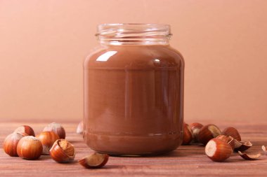 Renkli bir arka planda cam kavanozda çikolata ezmesi. Çikolata yağı, çikolata sosu..