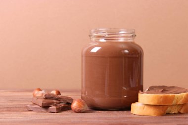 Renkli bir arka planda cam kavanozda çikolata ezmesi. Çikolata yağı, çikolata sosu..