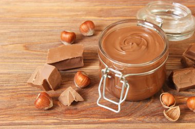 Renkli bir arka planda cam kavanozda çikolata ezmesi. Çikolata yağı, çikolata sosu..