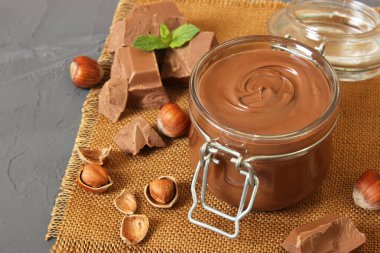 Renkli bir arka planda cam kavanozda çikolata ezmesi. Çikolata yağı, çikolata sosu..