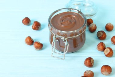 Renkli bir arka planda cam kavanozda çikolata ezmesi. Çikolata yağı, çikolata sosu..