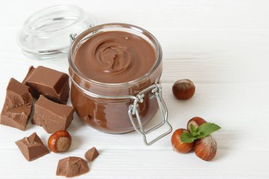 Renkli bir arka planda cam kavanozda çikolata ezmesi. Çikolata yağı, çikolata sosu..