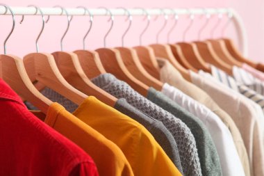 Renkli bir arka planda gardırop rafında asılı şık kıyafetler..