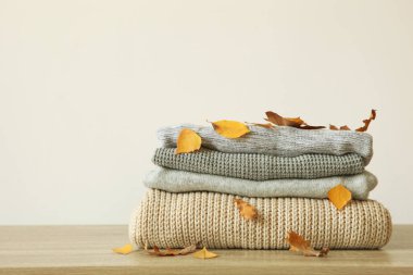 Masada bir yığın kalın kazak ve sonbahar yaprakları var..