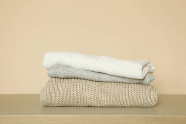 Masanın üzerinde renkli bir arka planda bir yığın kalın kazak var..