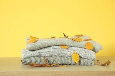 Masada bir yığın kalın kazak ve sonbahar yaprakları var..