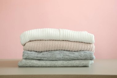 Masanın üzerinde renkli bir arka planda bir yığın kalın kazak var..