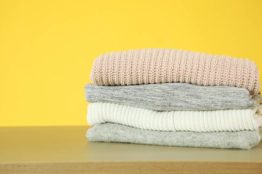 Masanın üzerinde renkli bir arka planda bir yığın kalın kazak var..