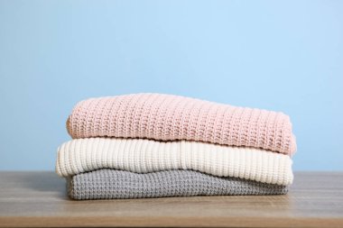 Masanın üzerinde renkli bir arka planda bir yığın kalın kazak var..