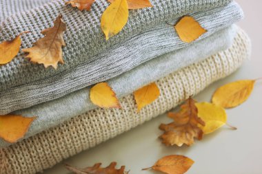 Masada bir yığın kalın kazak ve sonbahar yaprakları var..