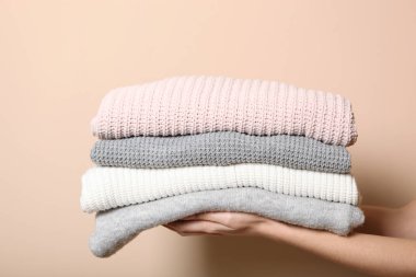 Renkli bir arka planda kadın ellerinde bir kazak yığını. Kalın kıyafetler..