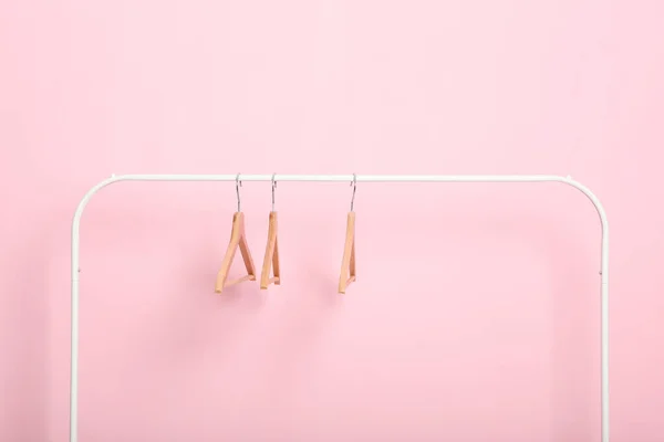 empty clothes hangers on a wardrobe rack on a colored background.