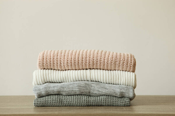 a stack of warm sweaters on the table on a colored background.