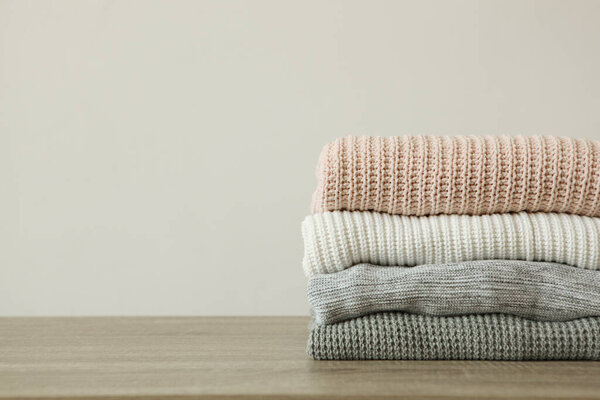 a stack of warm sweaters on the table on a colored background.