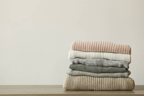 стопка теплых свитеров на столе на цветном фоне
.