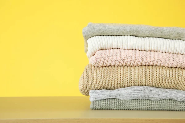 Una Pila Suéteres Calientes Sobre Mesa Sobre Fondo Color — Foto de Stock