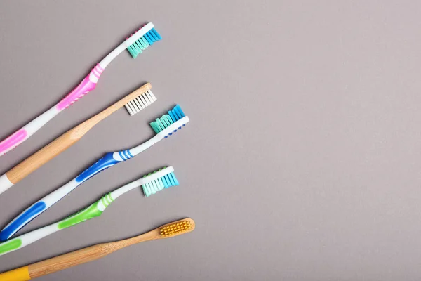 natural bamboo toothbrushes and plastic on a colored background top view.