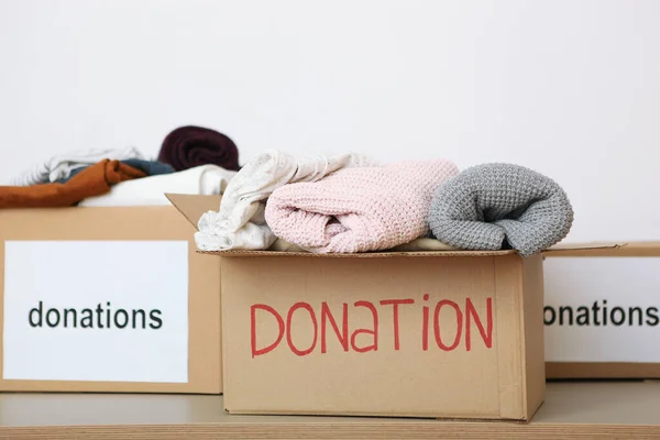 Lådor Med Donationer Med Nödvändiga Saker Bordet Färgad Bakgrund Välgörenhet — Stockfoto