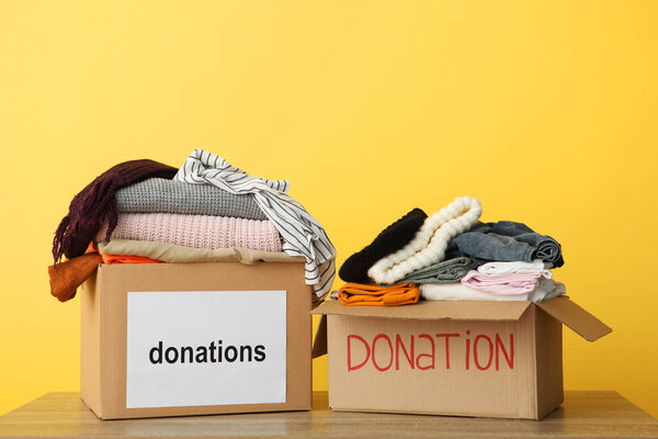 boxes with donations with the necessary things on the table on a colored background. Charity, volunteering.