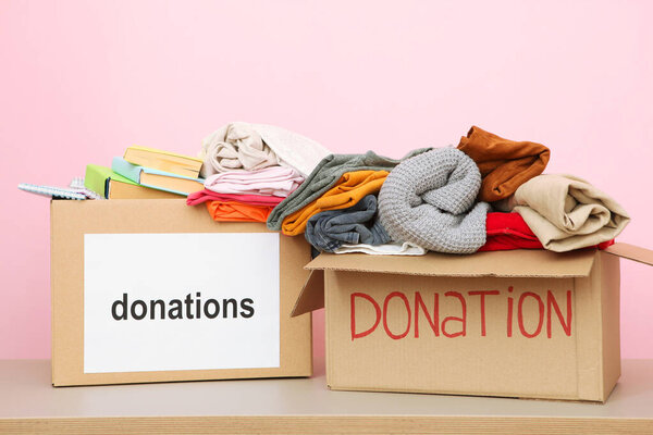 boxes with donations with the necessary things on the table on a colored background. Charity, volunteering.