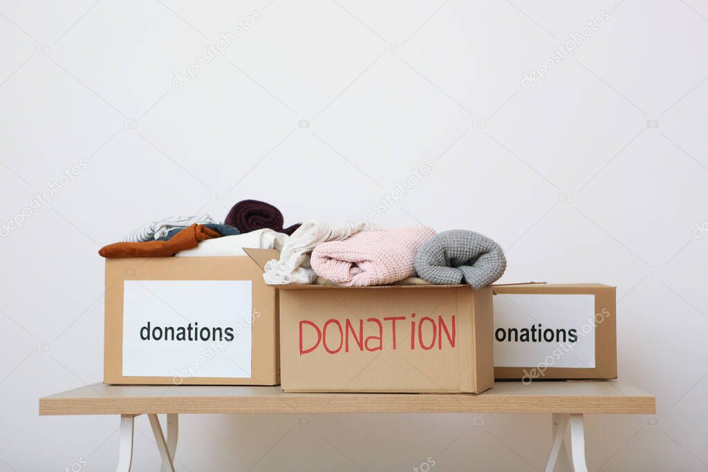 boxes with donations with the necessary things on the table on a colored background. Charity, volunteering.