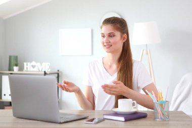 Kız, modern bir dizüstü bilgisayar kullanarak evden uzaktan çalışıyor..