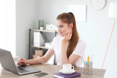 Kız, modern bir dizüstü bilgisayar kullanarak evden uzaktan çalışıyor..